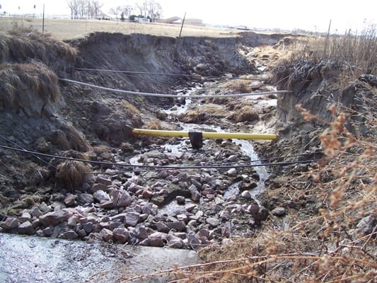 Erosion in the drainage has lead to exposure of utility lines.