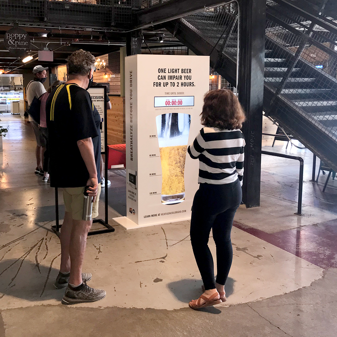 People interacting with One Light Beer Can Impair You for Up to 2 Hours Sign at the Stanley Marketplace in Denver detail image