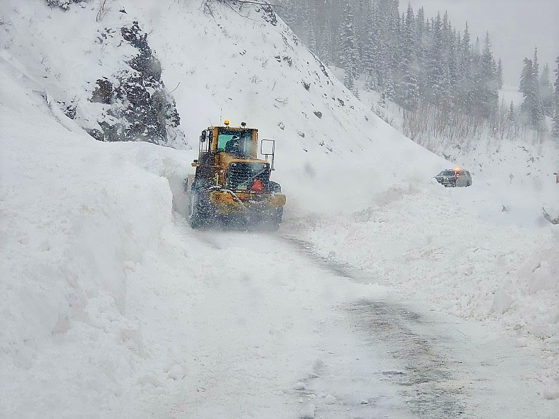 Snow plow tractor along a snowy mountain pass detail image