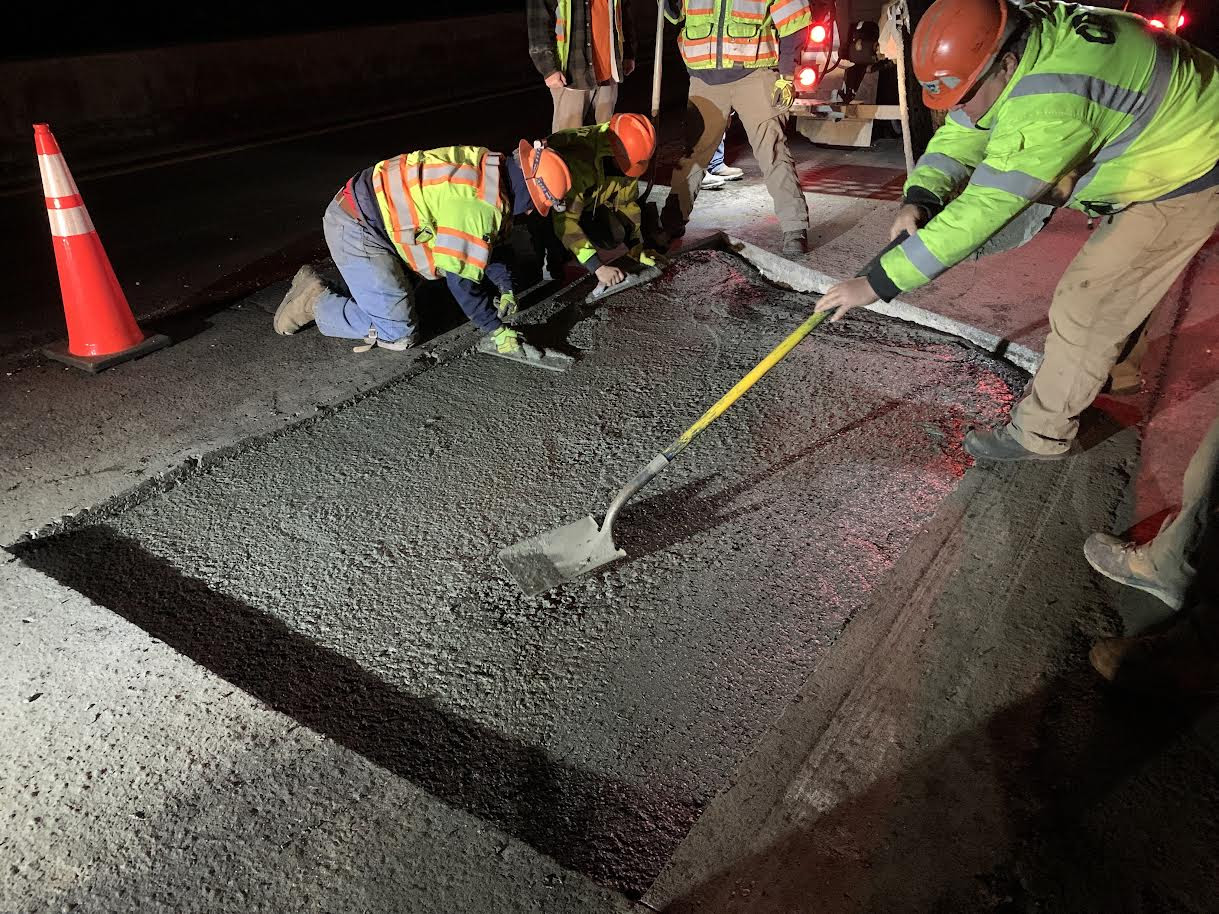 Crews repairing pavement at night detail image