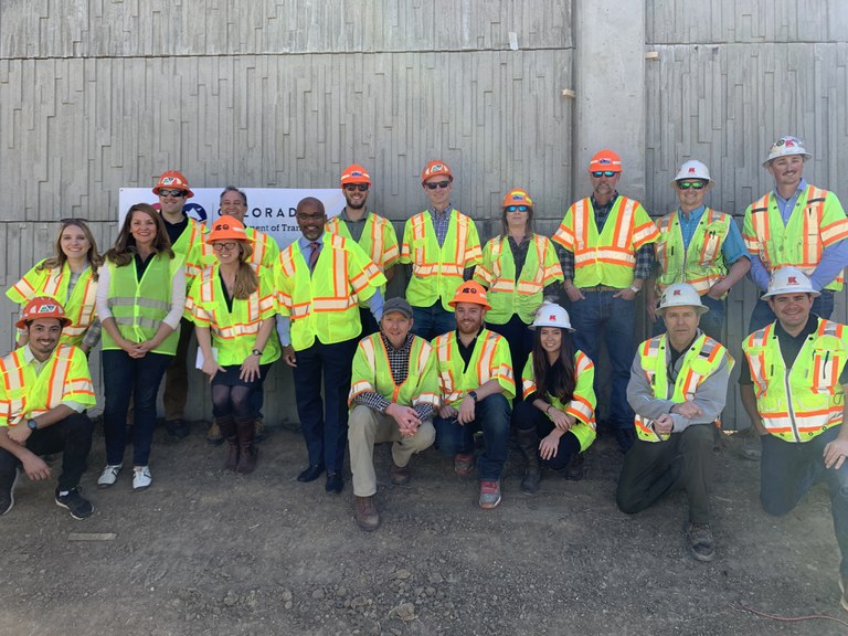 Denver City Councilwoman Amanda Sandoval, Congressman Ed Perlmutter, CDOT Executive Director Shoshana Lew, and Denver Mayor Michael B. Hancock join CDOT and contractor Kraemer North America project team members in front of a new concrete noise wall panel near I-70 and Lowell.