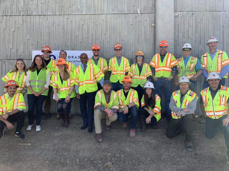 Denver City Councilwoman Amanda Sandoval, Congressman Ed Perlmutter, CDOT Executive Director Shoshana Lew, and Denver Mayor Michael B. Hancock join CDOT and contractor Kraemer North America project team members in front of a new concrete noise wall panel near I-70 and Lowell. Denver City Councilwoman Amanda Sandoval, Congressman Ed Perlmutter, CDOT Executive Director Shoshana Lew, and Denver Mayor Michael B. Hancock join CDOT and contractor Kraemer North America project team members in front of a new concrete noise wall panel near I-70 and Lowell.
