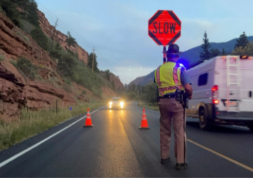State Trooper on the highway with a Slow sign detail image