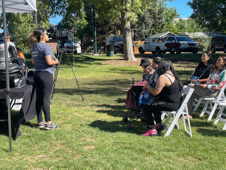 Woman speaking in front of crowd of people in a park