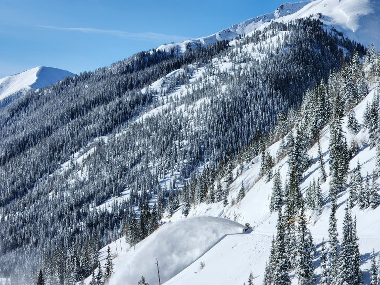 A CDOT snowblower casts an arc of snow off of the highway just below “The Ledges” snow slide path on US 550 south of the Red Mountain Pass summit. 