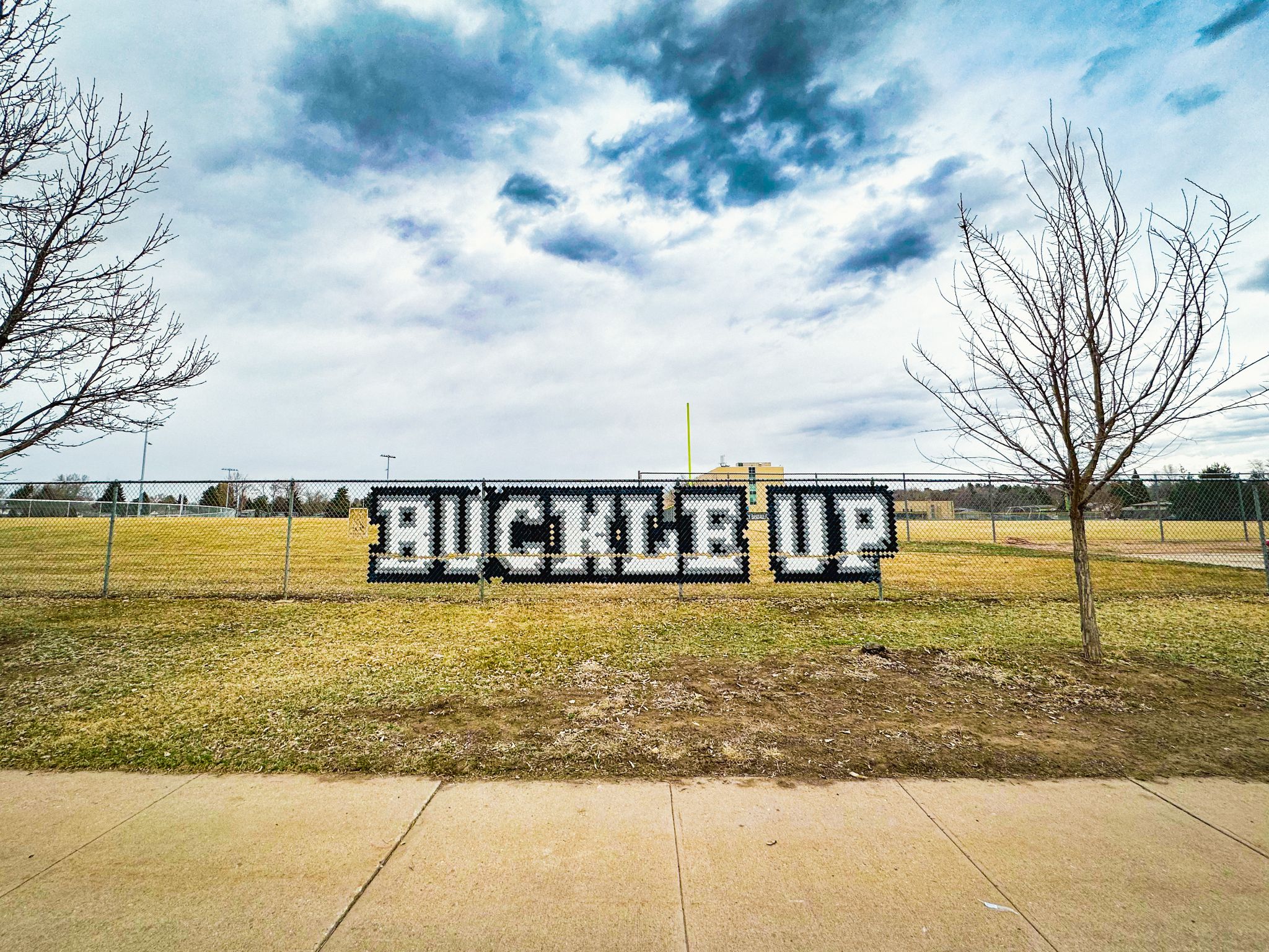 Buckle Up message installed with put-in cups in chain-link fence at John F Kennedy High School in Denver.jpg detail image