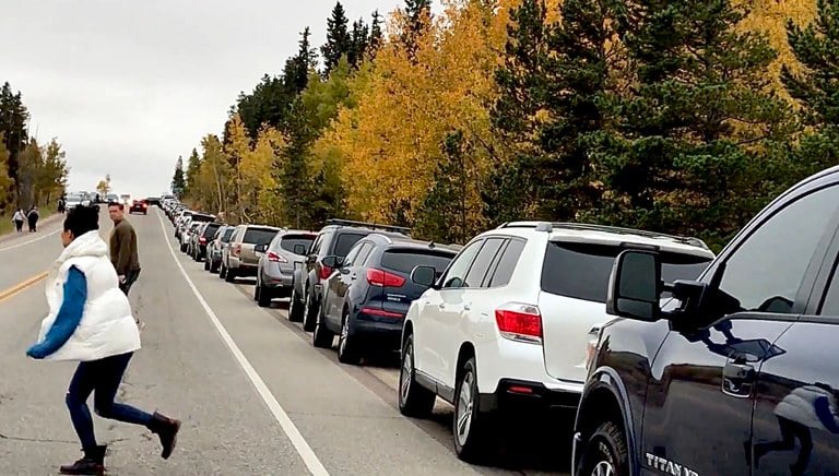 Several parked cars near US 285 Kenosha Pass and people crossing the highway to view the aspens turning gold. CDOT urges drivers to slow down and watch for people outside their vehicles and crossing roadways.