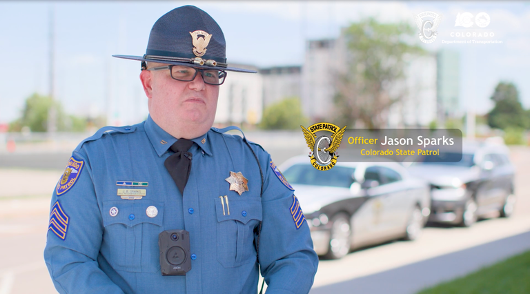 Colorado State Patrol trooper Jason Sparks standing in front two CSP vehicles Colorado State Patrol trooper Jason Sparks standing in front two CSP vehicles. The CSP and CDOT logos are in the top right corner.