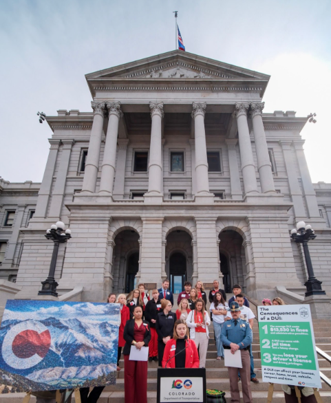 CDOT, CSP, AAA and MADD gather in front of the Colorado State Capitol to discuss the dangers of impaired driving. There is a poster board with a photo of Colorado’s mountains and another with the consequences of a DUI listed.