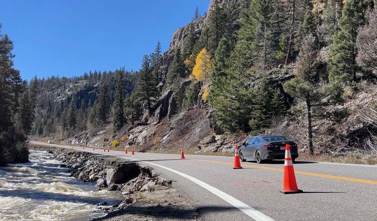 US 160 lined with traffic cones going up into the horizon beside surging waters in Rio Grande River.