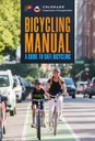 Cover of the Colorado Department of Transportation Bicycling Manual: A Guide to Safe Bicycling. The image features the Colorado Department of Transportation logo at the top. Below the text, a woman and a young boy, both wearing helmets, smile while riding bicycles in a green-painted dedicated bike lane on a city street with parked cars in the background. thumbnail image