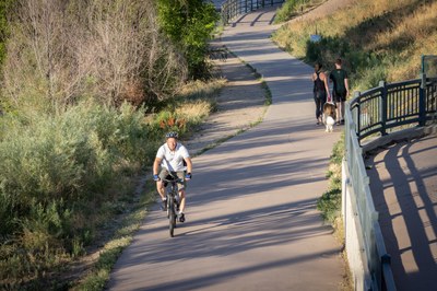 A bicyclists and some pedestrians use a Denver trail. 
