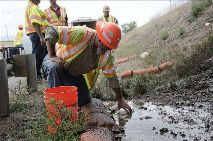 A CDOT environmental engineer collects samples to assess potential environmental impacts of bridge cleaning on ground water.