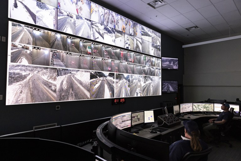 A control center room at the Eisenhower-Johnson Memorial Tunnel with operators monitoring a wall of cameras.
