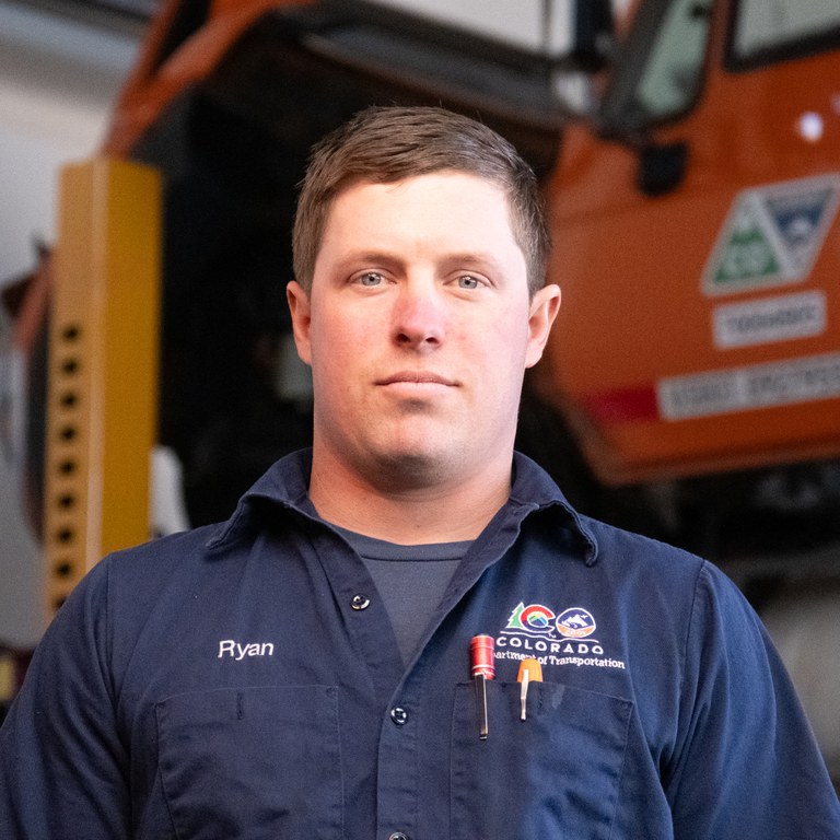 CDOT mechanic Ryan Smith stands in front of a truck on a hoist at CDOT’s Section 2 Maintenance facility in Grand Junction, Colorado