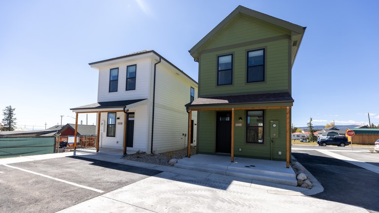 Parking lot and two newly constructed homes set against a backdrop of sunny blue skies.