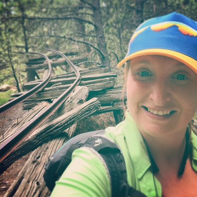 Photo of Brittany Samm in the foreground with old train tracks in the background.