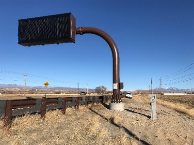 Looking at a VMS from the shoulder of the road with a guardrail running along the road.