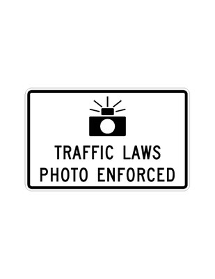Example of signage used in a speed enforcement corridor. A small, rectangular sign with the text, “traffic laws photo enforced” above a camera icon, indicates the presence of traffic or speed enforcement cameras.