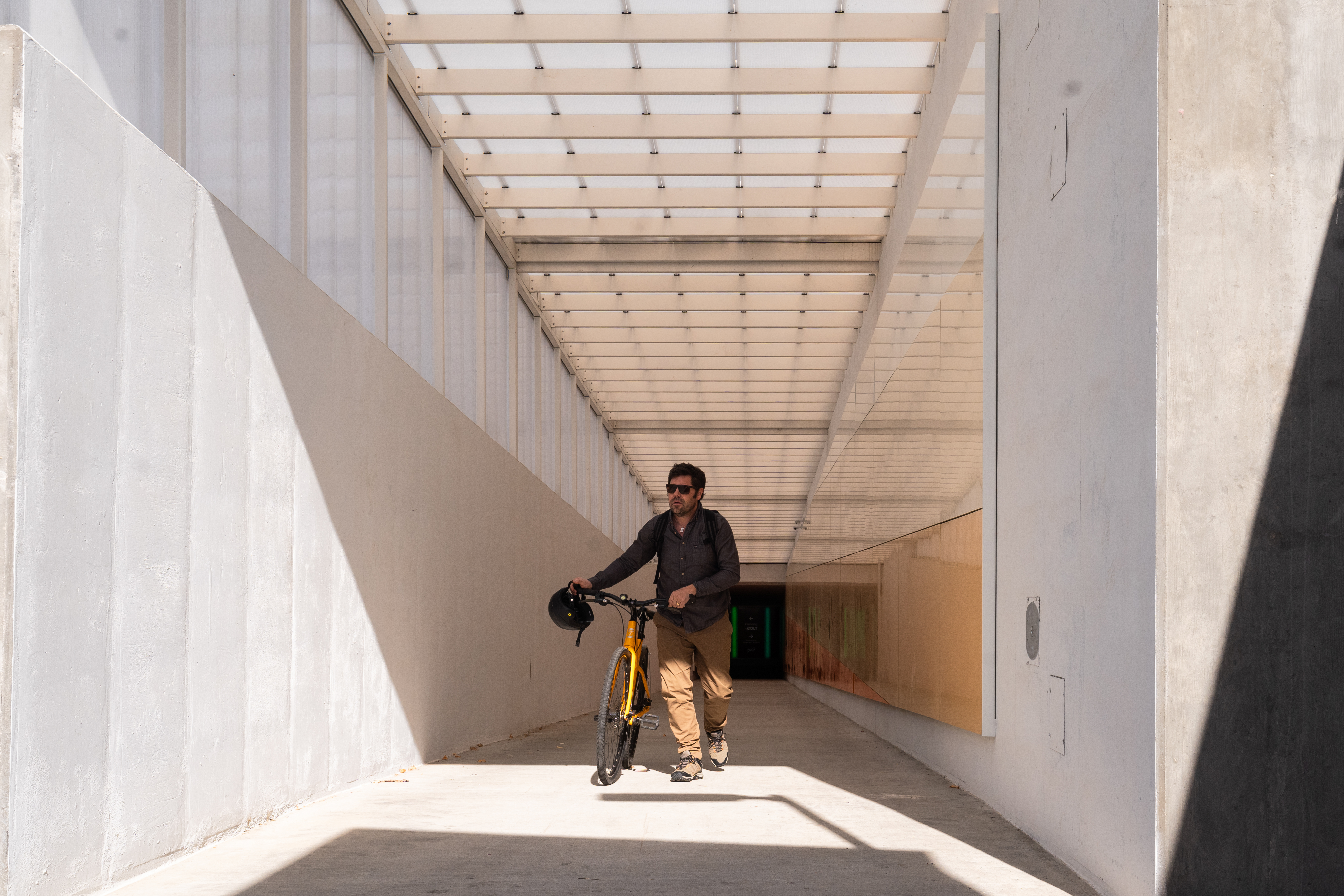 A man walking his bike exiting the mobility hub