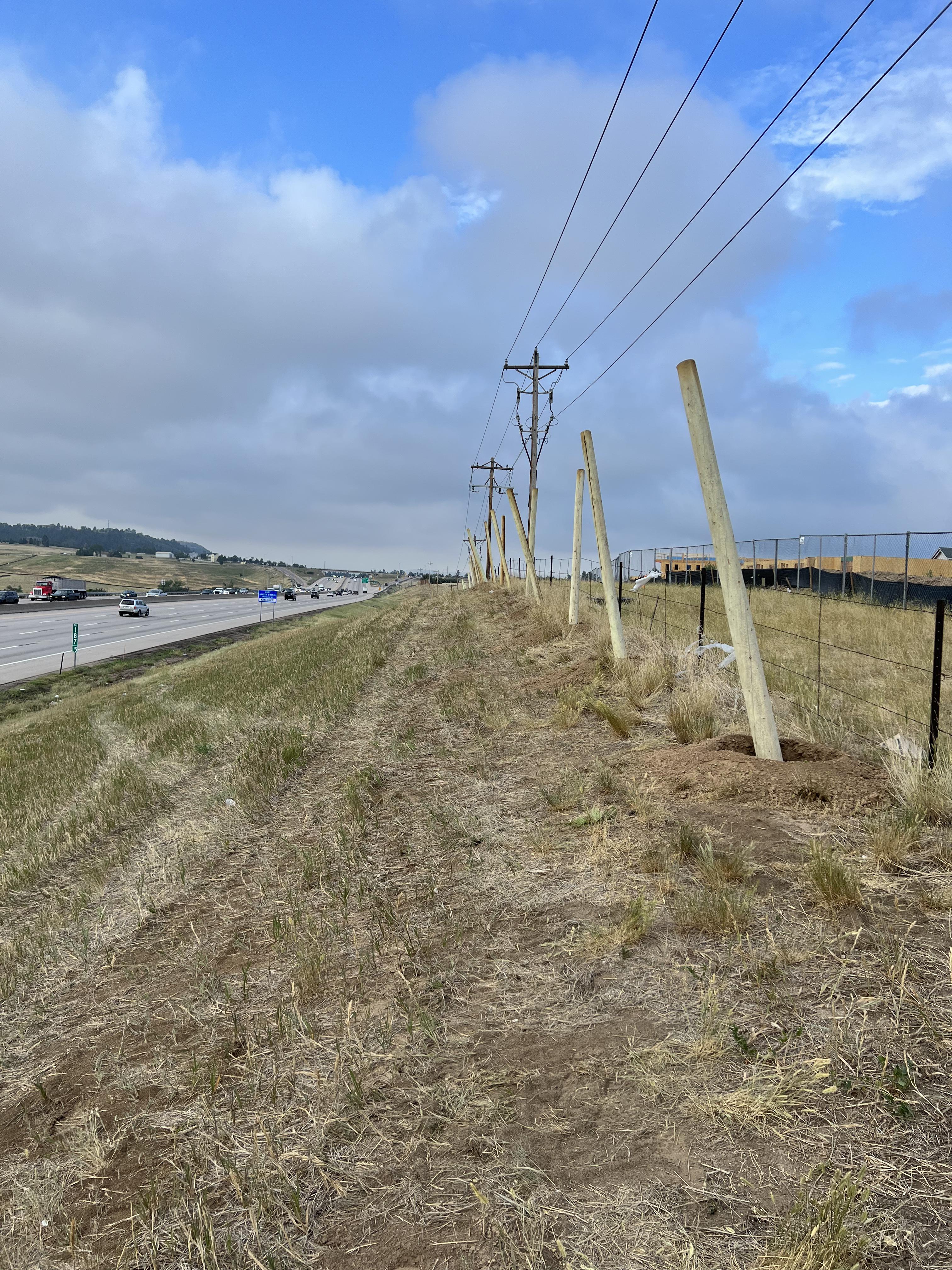 Timber poles are installed on I-25 for wildlife fencing detail image