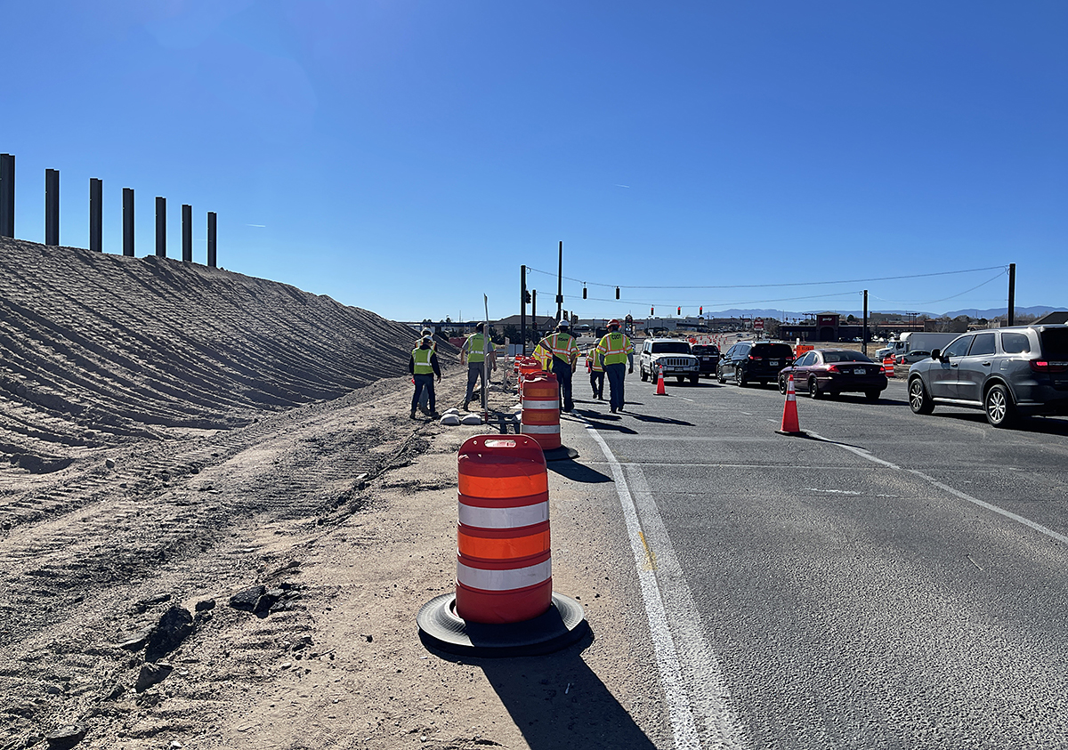 Traffic and workers in road with posts up to left detail image