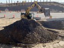 Large excavator on top of pile of dirt with posts in background thumbnail image
