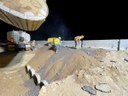 Workers look down to ground on top of large pile of dirt (at night) thumbnail image