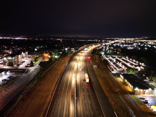 New auxiliary lanes on Interstate 25 between Fillmore Street and Garden of the Gods Road at night, illuminated by passing car headlights.