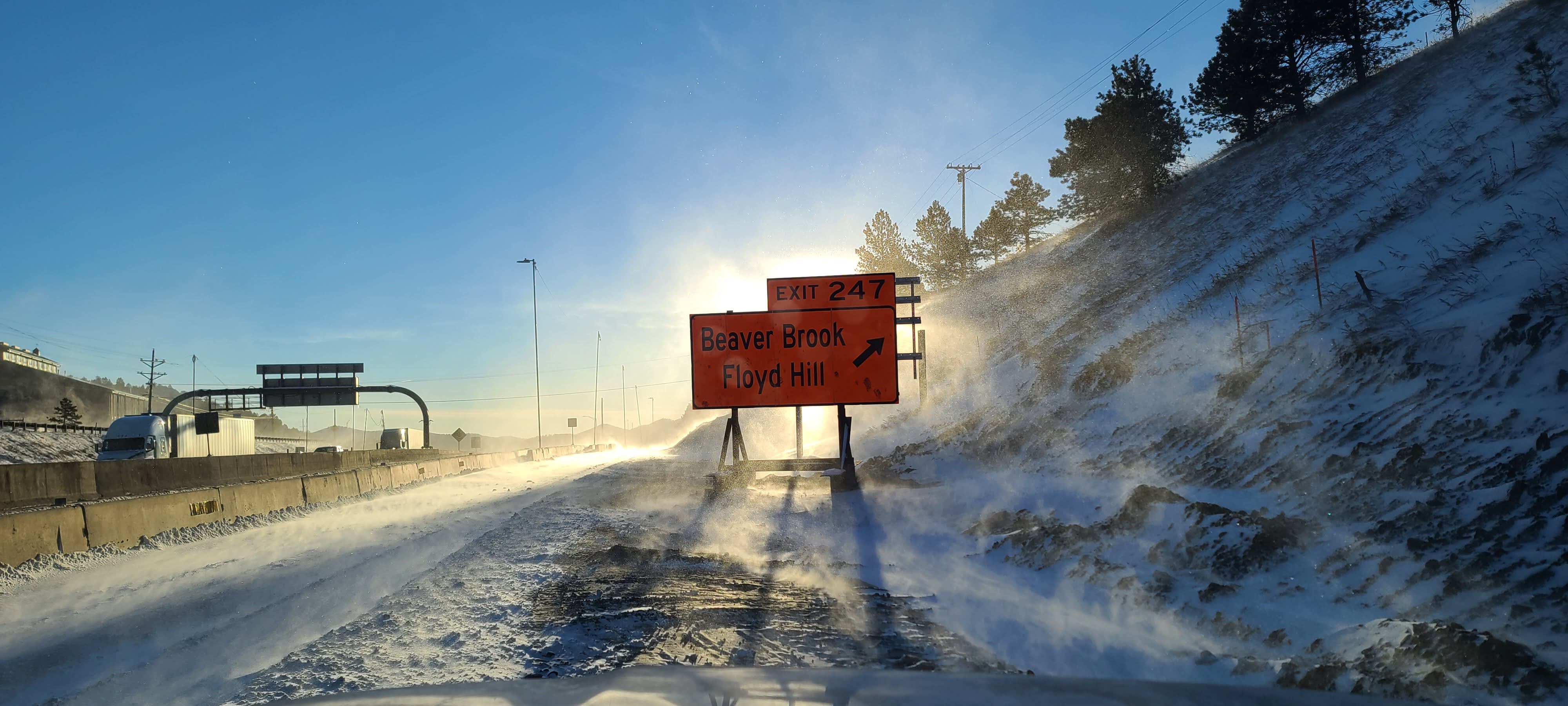 Road sign with blowing snow and bright sun. detail image
