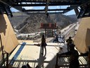 Construction workers standing inside a bridge segment traveler looking out over a mountain canyon highway project. thumbnail image