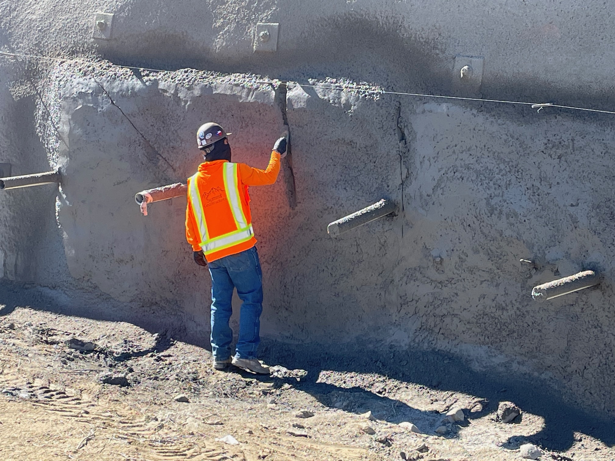 Construction crews spraying concrete on side of hill. detail image
