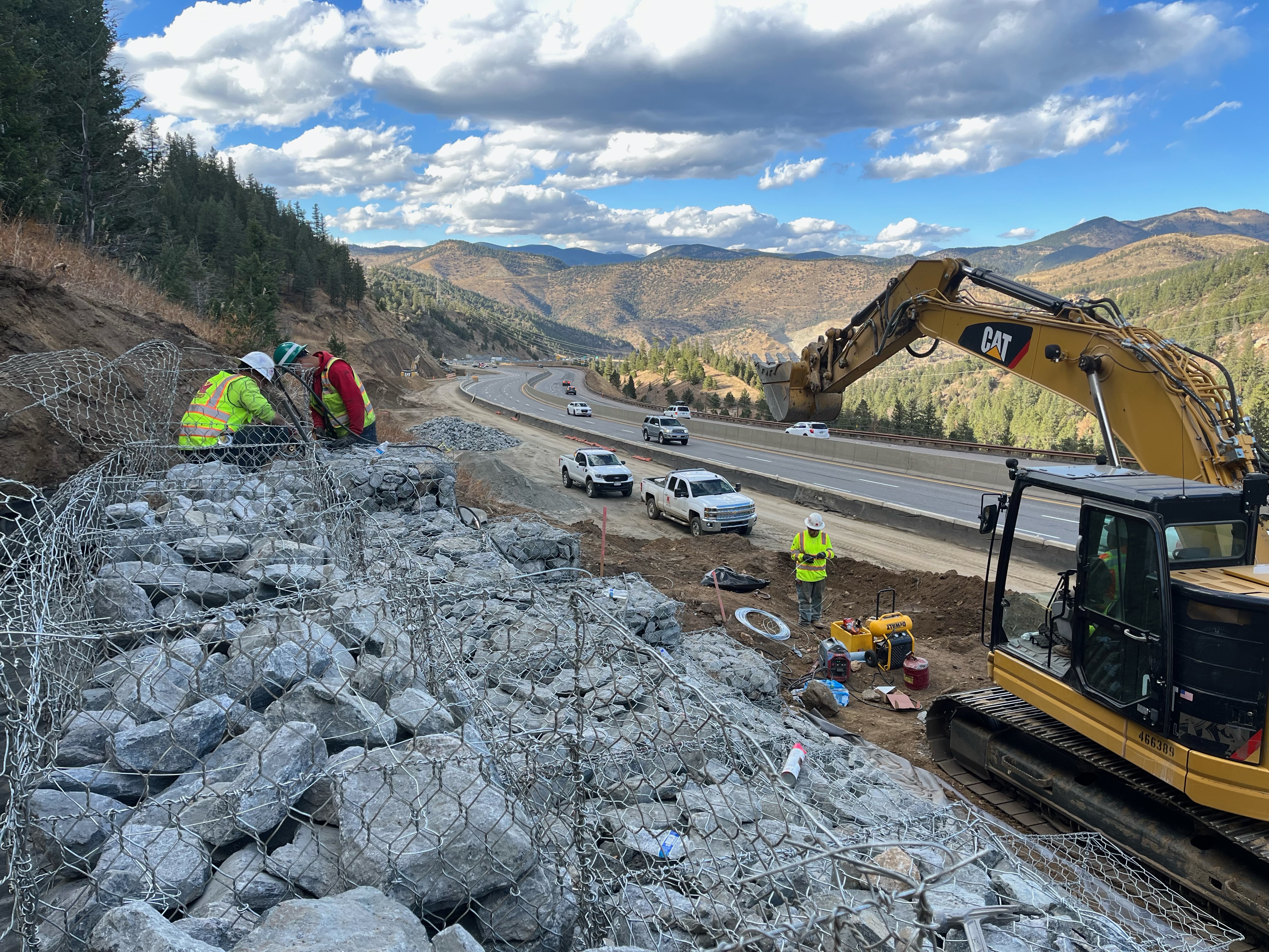 Crews setting rock and wire on hillside to help with drainage in the area. detail image