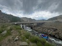 Two rafts in Clear Creek floating down the river under a bridge with dark clouds above. thumbnail image
