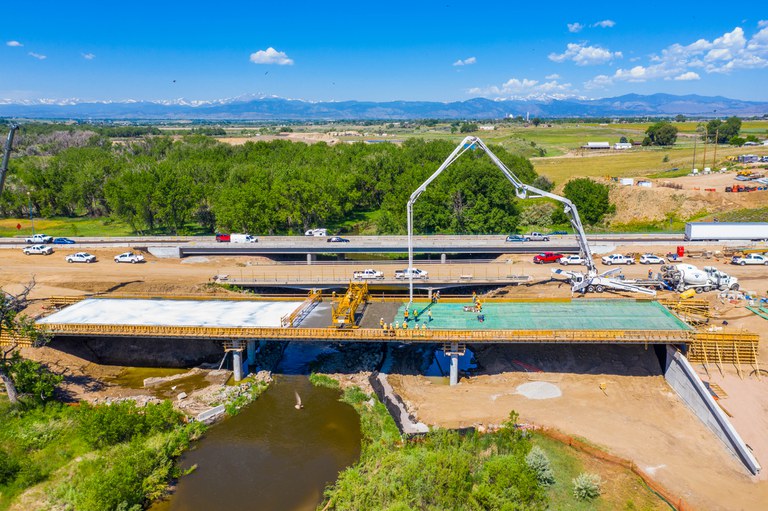 Side view of construction crews pouring concrete on the Big Thompson East Frontage Road