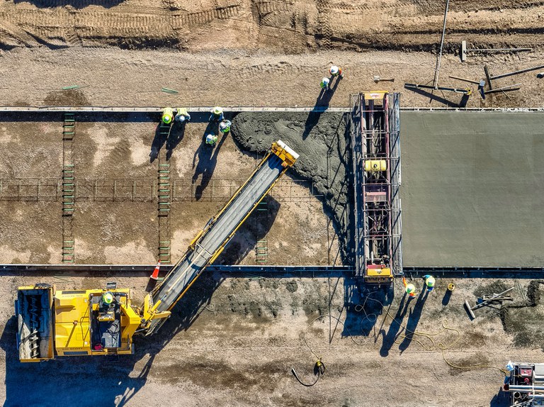 Bird's eye view of construction crews pouring concrete for new lanes on I-25