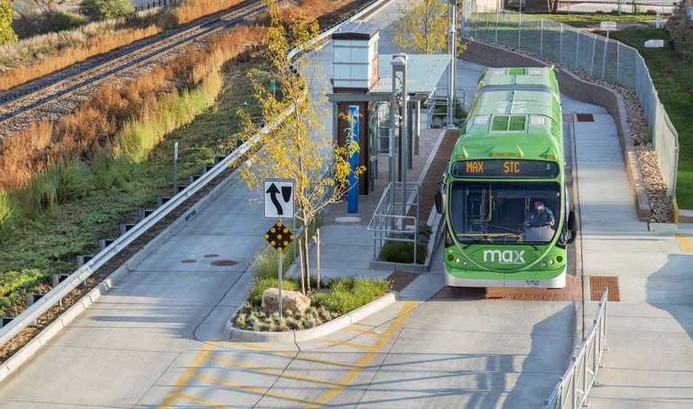 Shelter at the MAX bus rapid transit station in Fort Collins, CO. It features stainless steel pillars and a frosted angled shelter top. The station includes benches, ticket vending machines and a map.