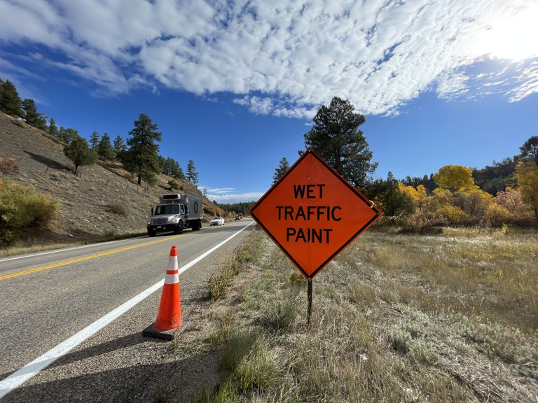 Orange "Wet Traffic Paint" sign beside US Highway 160 in Archuleta County