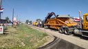 The mill machine is milling the existing asphalt surface, conveying the millings into haul trucks to be dumped off-site in preparation for the asphalt overlay thumbnail image