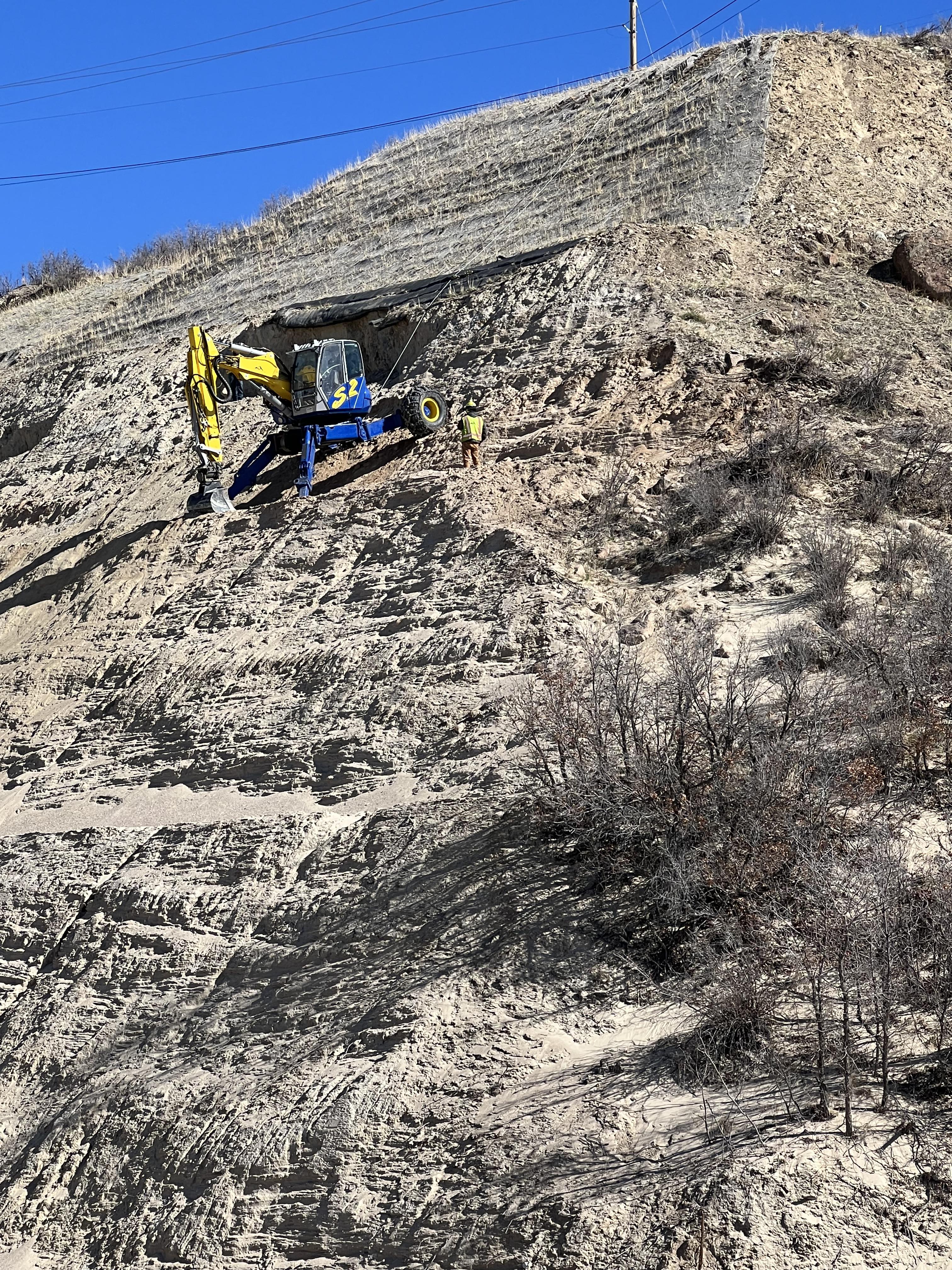 April 8, 2022. Using a spider excavator, loose rock and material is worked off the slope where it can be carried away. detail image