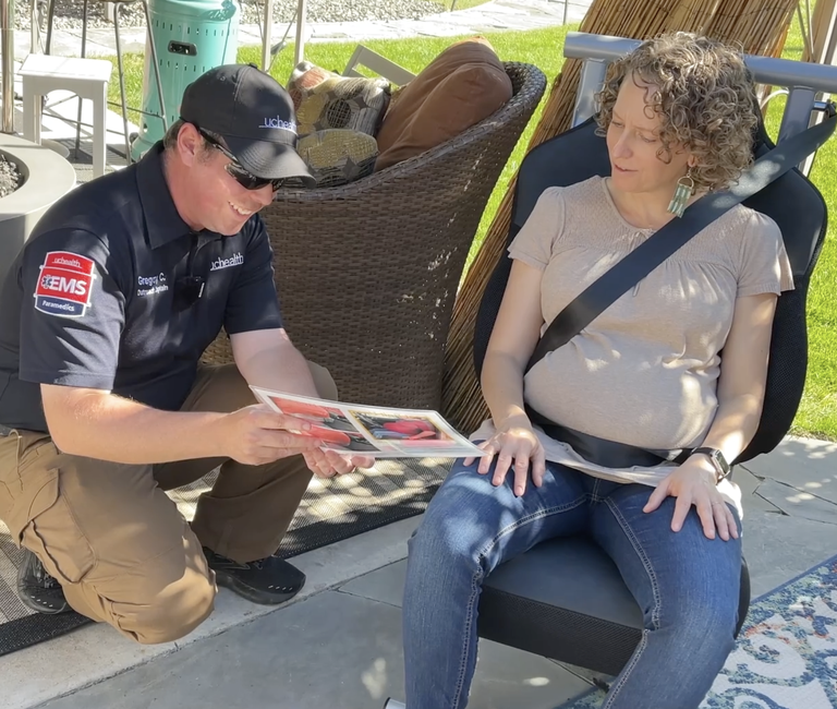 Car seat technician showing a seat belt safety pamphlet to a pregnant women buckled correctly in a car seat. 