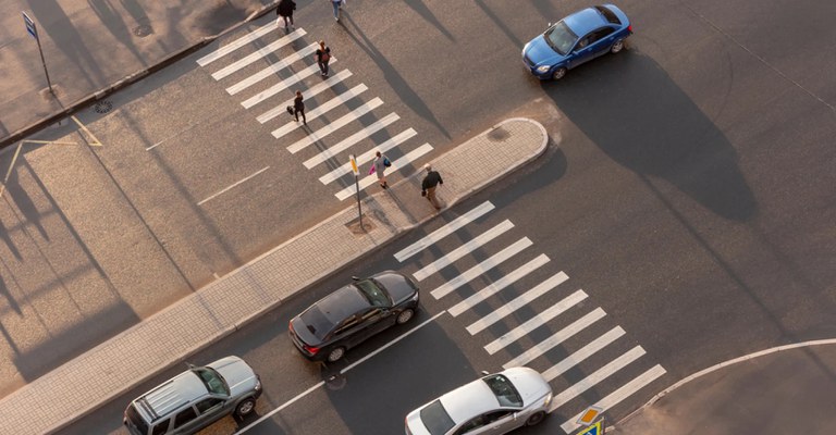 Pedestrians crossing the street while cars idle in the road