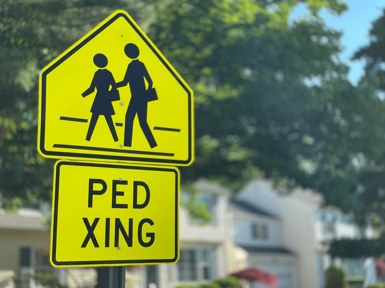 A pedestrian crossing sign in a sunny neighborhood.