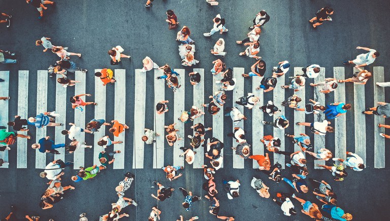 Aerial view of dozens of pedestrians using a crosswalk.