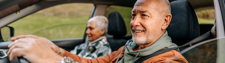 Research on older drivers Older man driving a vehicle with an older woman in the passenger seat.