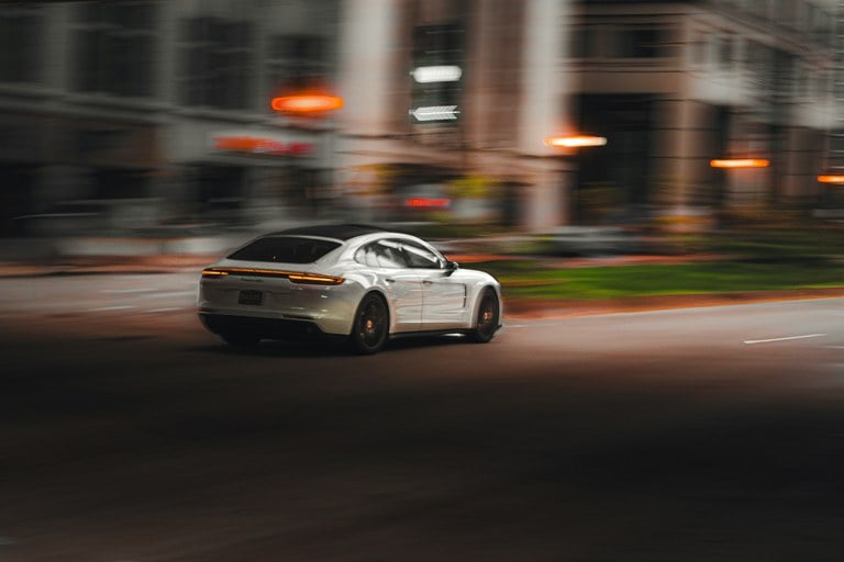 White car speeding on an empty downtown street at night.