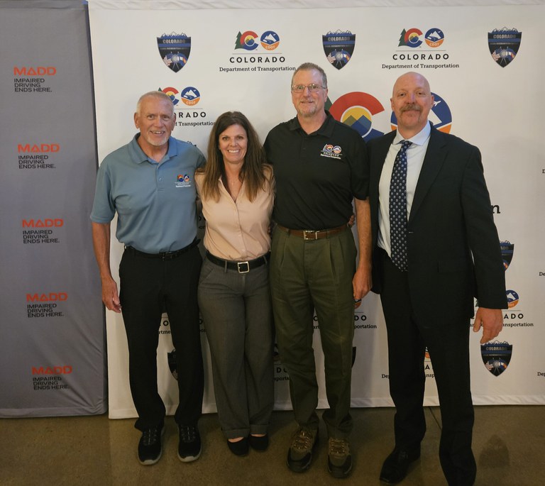 Law Enforcement Liaison team members standing in front of a banner with the CDOT and MADD logos. 