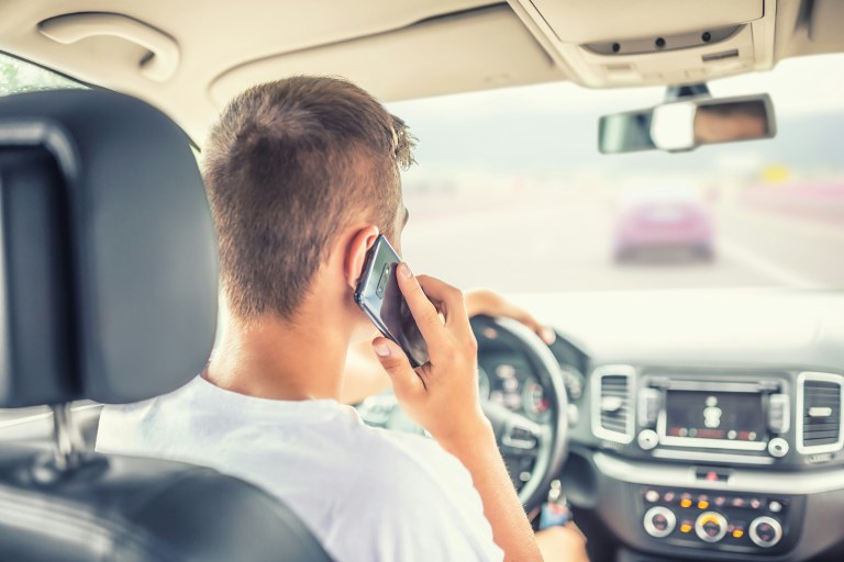 Man driving car and holding cellphone up to his right ear.