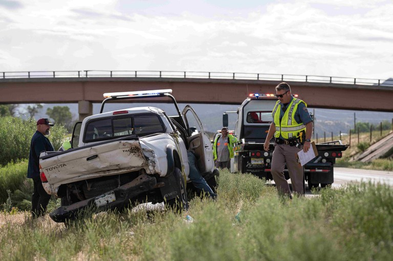 Hit and Run Crash Colorado State Patrol trooper at the scene of a car crash. A white pickup truck is being loaded onto a tow truck.