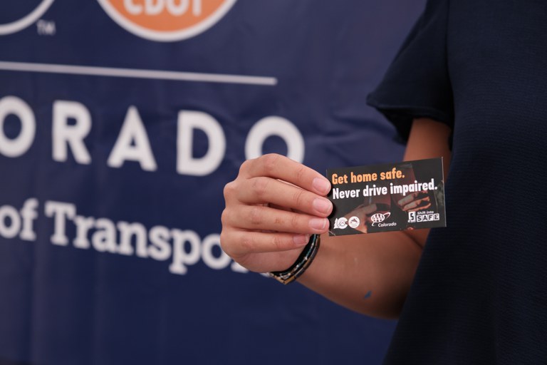 Civic Center Night Market A hand holding up a business card that reads: “Get home safe. Never drive impaired.”
